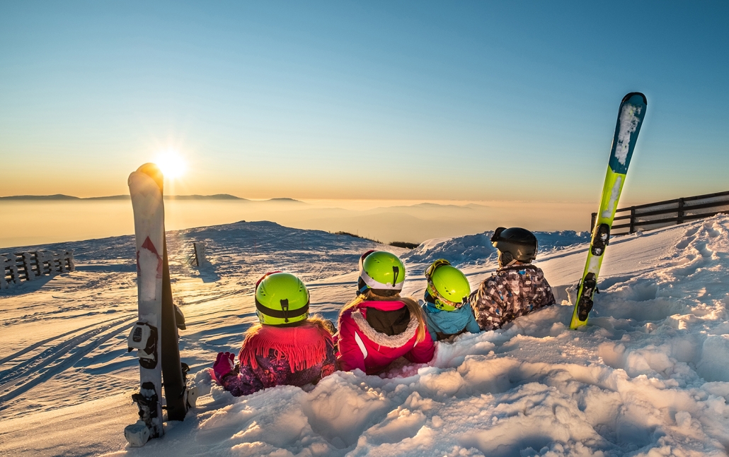 A family watching the sunset and laying in the snow on a vacation in Belgrade, Montana.